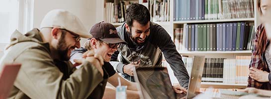 Three men laughing over a computer