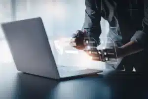 Individual holding a phone in front of an open laptop